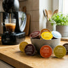 Dolce Gusto Kaffeemaschine mit bunten Kaffeekapseln und verschiedenen Kaffeespezialitäten in Tassen