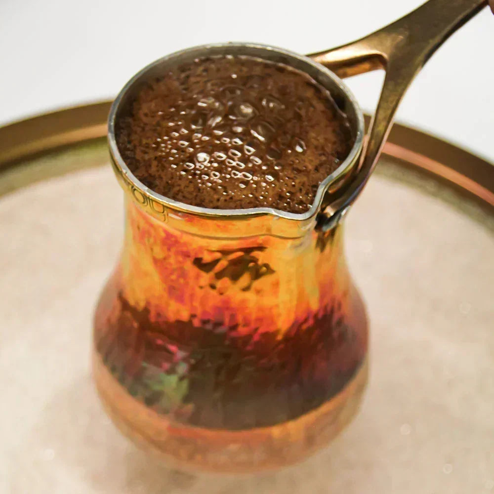 Türkischer Mokka in kleiner Tasse neben Mokkakanne, Kaffeepulver und orientalischem Gebäck